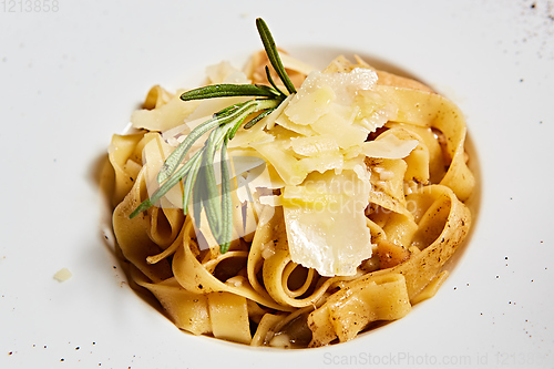 Image of Close-up italian pasta plate with grated parmesan cheese and basil leaf