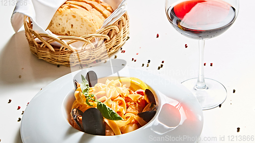 Image of The cooked mussels and pasta with wine glass.