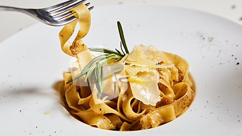 Image of Close-up italian pasta plate with grated parmesan cheese and basil leaf