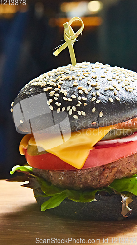 Image of Japanese Black Burger with Cheese. Cheeseburger from Japan with black bun on dark background.