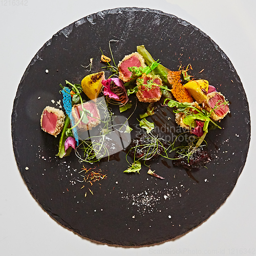 Image of Close up of rare seared Ahi tuna slices with fresh vegetable salad on a plate.