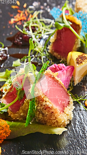 Image of Close up of rare seared Ahi tuna slices with fresh vegetable salad on a plate.