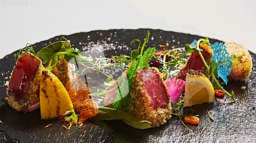 Image of Close up of rare seared Ahi tuna slices with fresh vegetable salad on a plate.