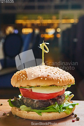 Image of Beef burger with lettuce and mayonnaise served on a rustic wooden table of counter, with copy space.