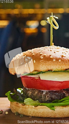 Image of Beef burger with lettuce and mayonnaise served on a rustic wooden table of counter, with copy space.