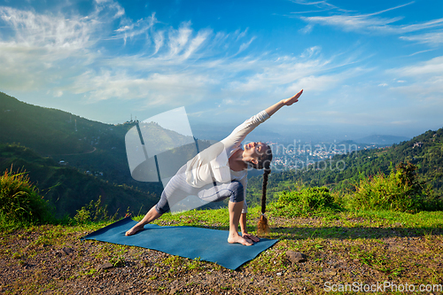 Image of Woman practices yoga asana outdoors