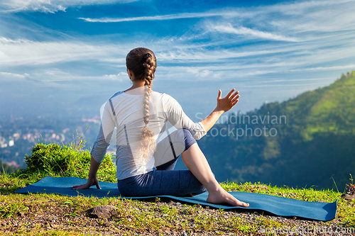Image of Woman practices yoga asana Marichyasana