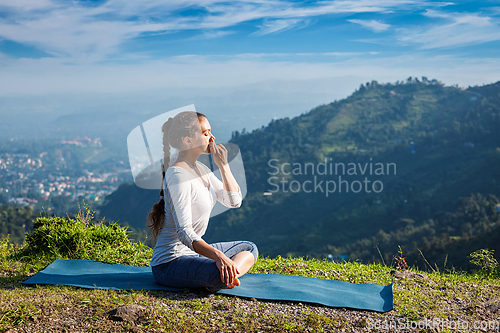 Image of Woman practices pranayama in lotus pose outdoors