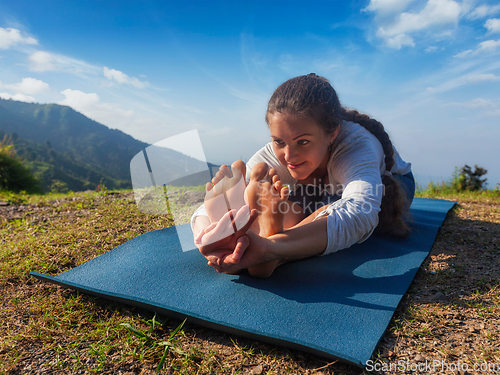 Image of Woman doing yoga asana Paschimottanasana forward bend