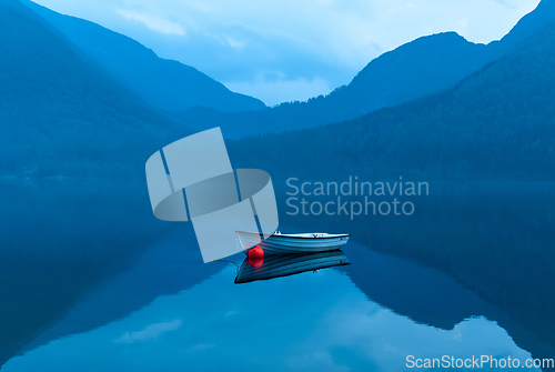 Image of small rowing boat reflects in the water in the blue hour