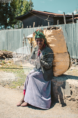 Image of Ethiopian woman resting with sack of charcoal, Ethiopia