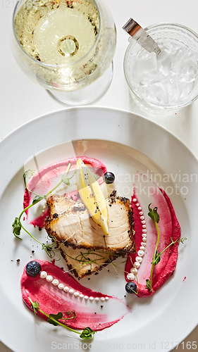 Image of White fish with lemon on white plate, selective focus