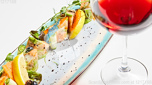 Image of fried fish rolls with herbs and vegetables on blue plate.