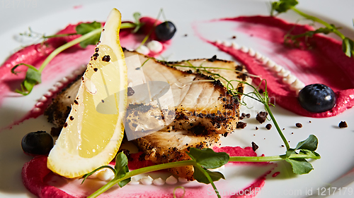 Image of White fish with lemon on white plate, selective focus