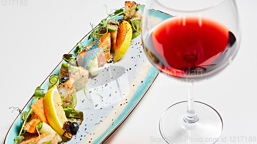 Image of fried fish rolls with herbs and vegetables on blue plate.