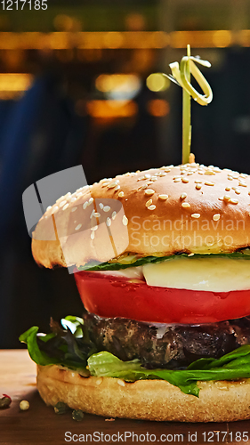 Image of Beef burger with lettuce and mayonnaise served on a rustic wooden table of counter, with copy space.