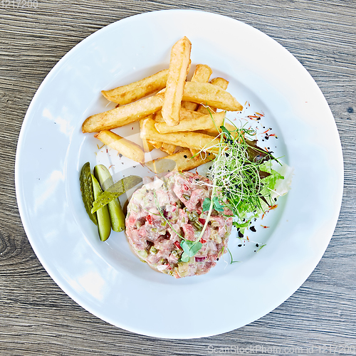 Image of Meat tartar with french fries and vegetable salad.