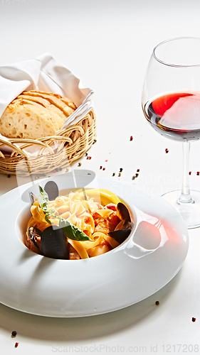 Image of The cooked mussels and pasta with wine glass.