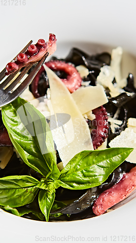 Image of Pasta with black cuttlefish ink, octopuses and parmesan.