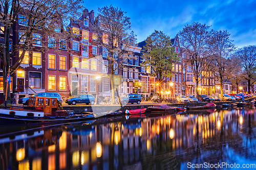 Image of Amterdam canal, boats and medieval houses in the evening