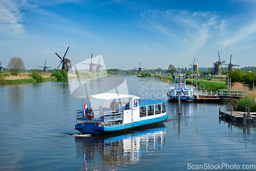 Image of Netherlands rural lanscape with tourist boat and windmills at famous tourist site Kinderdijk in Holland