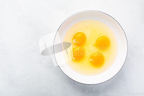 Image of Raw eggs, top view of four raw eggs yolk in bowl on white background