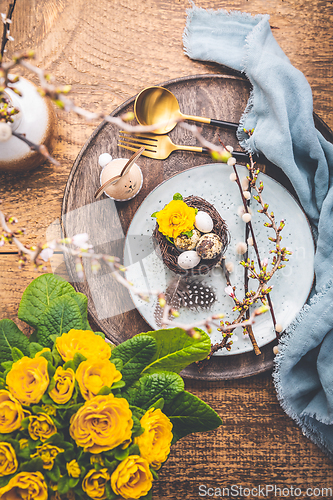 Image of Easter table setting with spring flowers and cutlery on wooden table