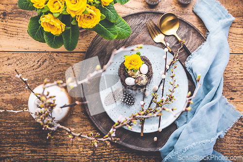 Image of Easter table setting with spring flowers and cutlery on wooden table