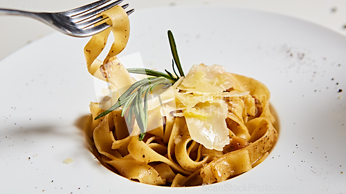 Image of Close-up italian pasta plate with grated parmesan cheese and basil leaf