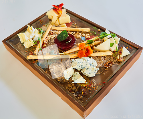 Image of Cheese selection on wooden rustic board. Cheese platter with different cheeses on wood.