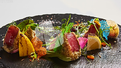 Image of Close up of rare seared Ahi tuna slices with fresh vegetable salad on a plate.