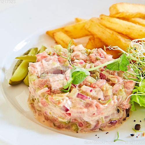 Image of Meat tartar with french fries and vegetable salad.