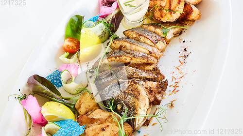 Image of The fried fish on plate with vegetables. Shallow dof.