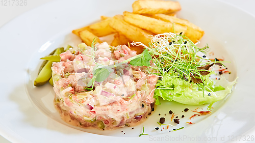 Image of Meat tartar with french fries and vegetable salad.