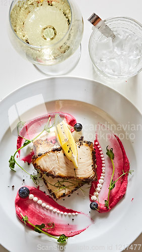 Image of White fish with lemon on white plate, selective focus