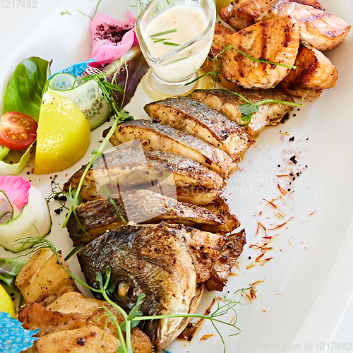 Image of The fried fish on plate with vegetables. Shallow dof.