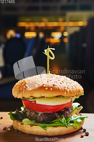 Image of Beef burger with lettuce and mayonnaise served on a rustic wooden table of counter, with copy space.