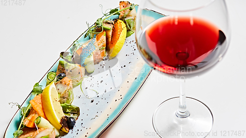 Image of fried fish rolls with herbs and vegetables on blue plate.