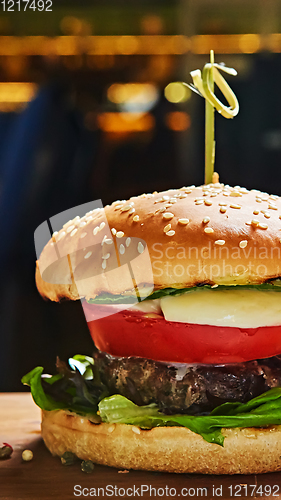 Image of Beef burger with lettuce and mayonnaise served on a rustic wooden table of counter, with copy space.