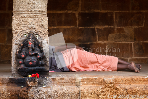 Image of Man sleeping behing the column with Ganesha images. in Hindu tem