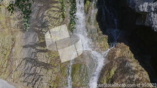 Image of Big beautiful waterfall flows down the rocks mountains