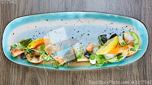 Image of fried fish rolls with herbs and vegetables on blue plate.