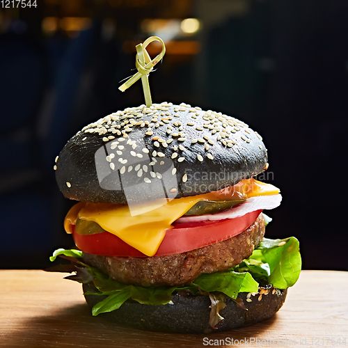 Image of Japanese Black Burger with Cheese. Cheeseburger from Japan with black bun on dark background.