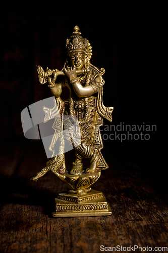 Image of Krishna statue on wooden background