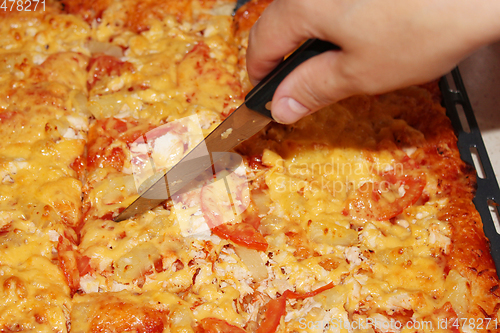 Image of appetizing home pizza cutting by knife