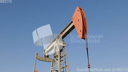 Image of Operating oil and gas well in oil field, profiled against the blue sky