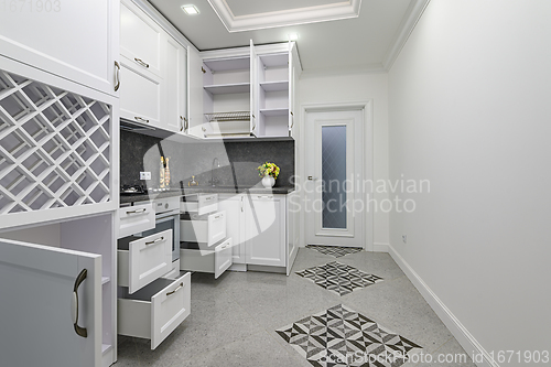 Image of Open doors and drawers open at modern white kitchen