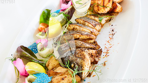 Image of The fried fish on plate with vegetables. Shallow dof.