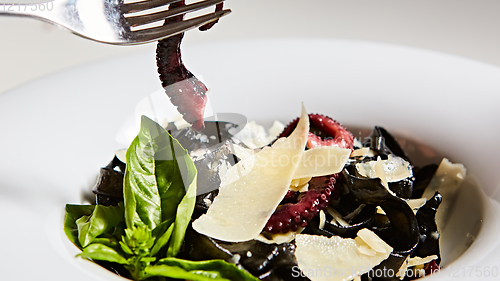 Image of Pasta with black cuttlefish ink, octopuses and parmesan.