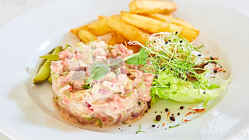 Image of Meat tartar with french fries and vegetable salad.